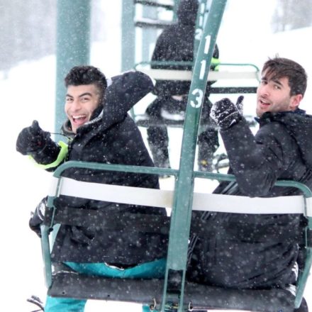 Students riding a ski lift while it's snowing